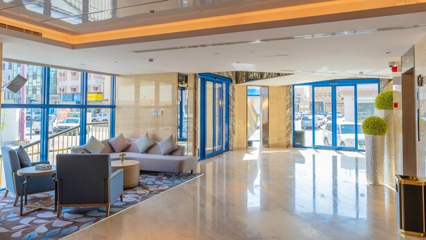 A spacious lobby with a modern design, featuring a sofa, chairs, and a coffee table.