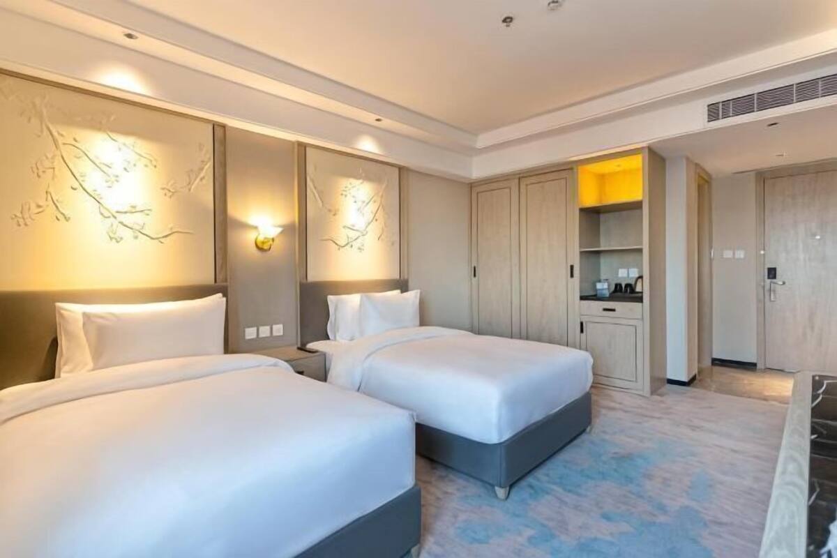 Ein Hotelzimmer mit zwei Betten, einer kleinen Küchenzeile und einem Badezimmer.