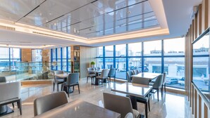 A modern interior with glass walls, a dining area, and a view of the city.
