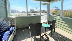 Eine überdachte Veranda mit Blick auf Häuser und Strandbepflanzung.