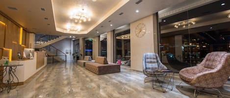 A spacious lobby with a reception desk, seating area, and a staircase leading to upper floors.