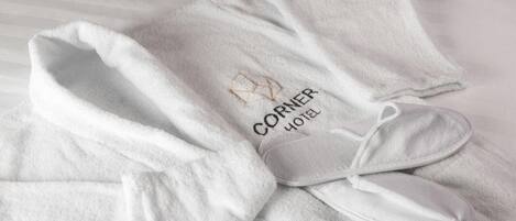 Un asciugamano bianco piegato con cura, con un logo e la scritta "CORNER HOTEL" su un letto.