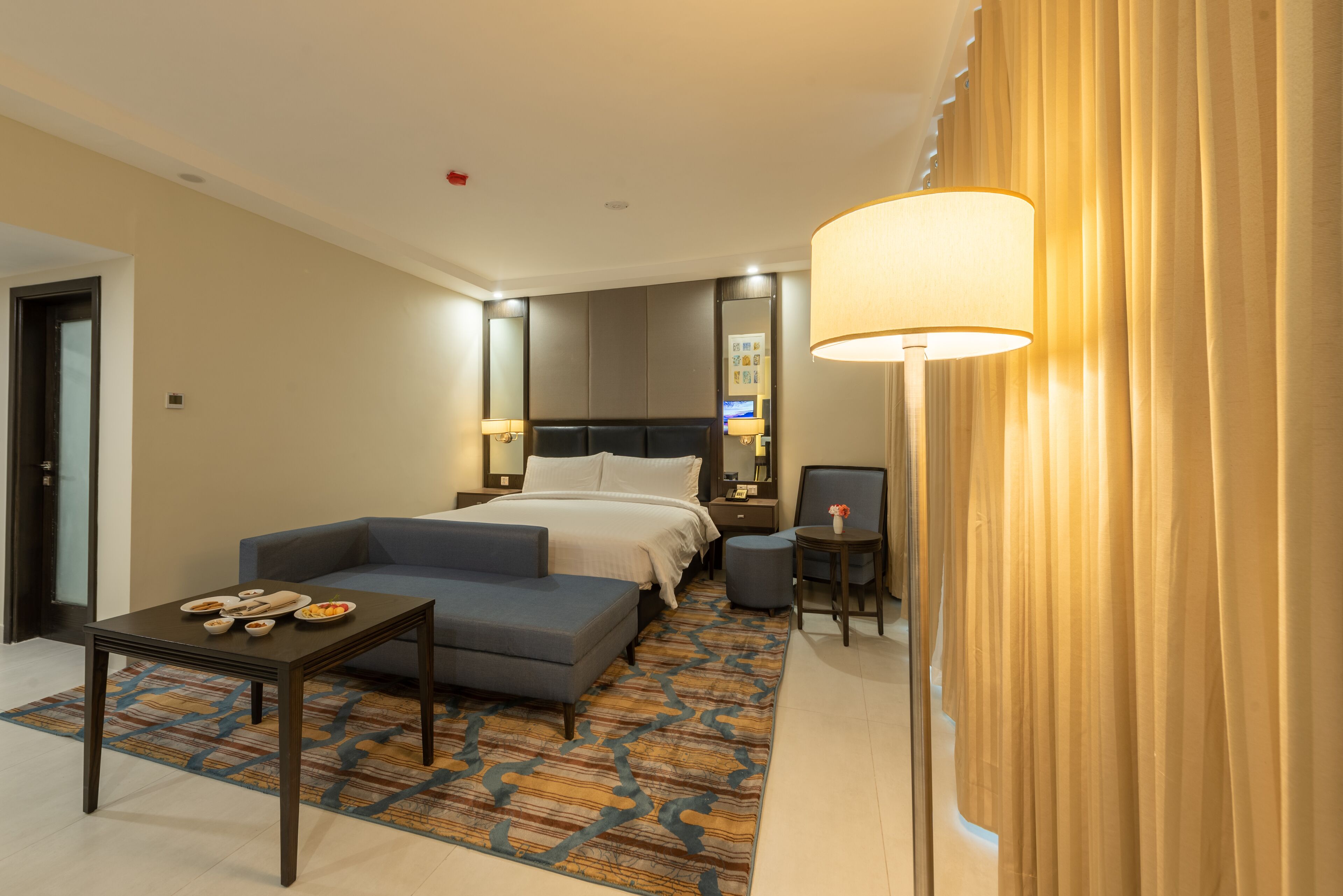 Una habitación de hotel con una cama, un sofá, una mesita y una silla.