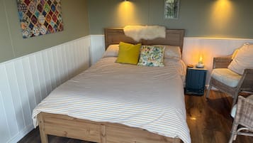 A neatly made bed with striped bedding, a wooden headboard, and two pillows, one yellow and one with a nature print.
