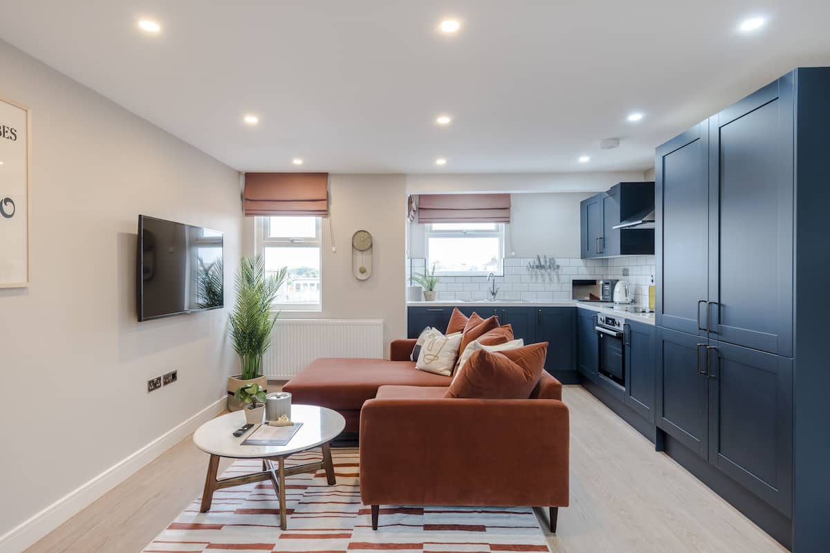 A modern living room with a sofa, a TV, and a dining area.