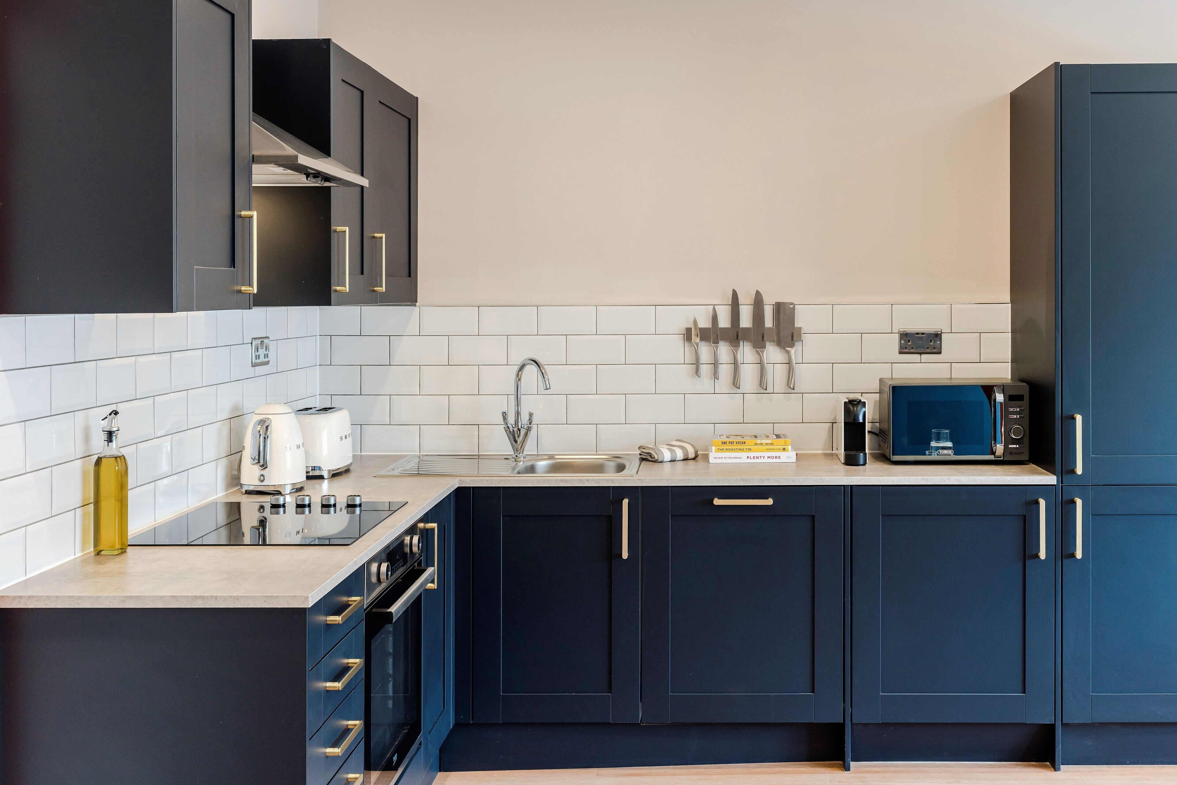Una cocina moderna con armarios oscuros, un lavamanos de acero inoxidable y un microondas.