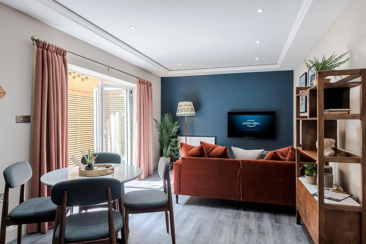 A modern living room with a sofa, chairs, a TV, and a dining area.