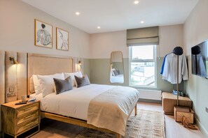 Un dormitorio moderno con una cama grande, mesitas de noche, un espejo y una ventana con vistas.