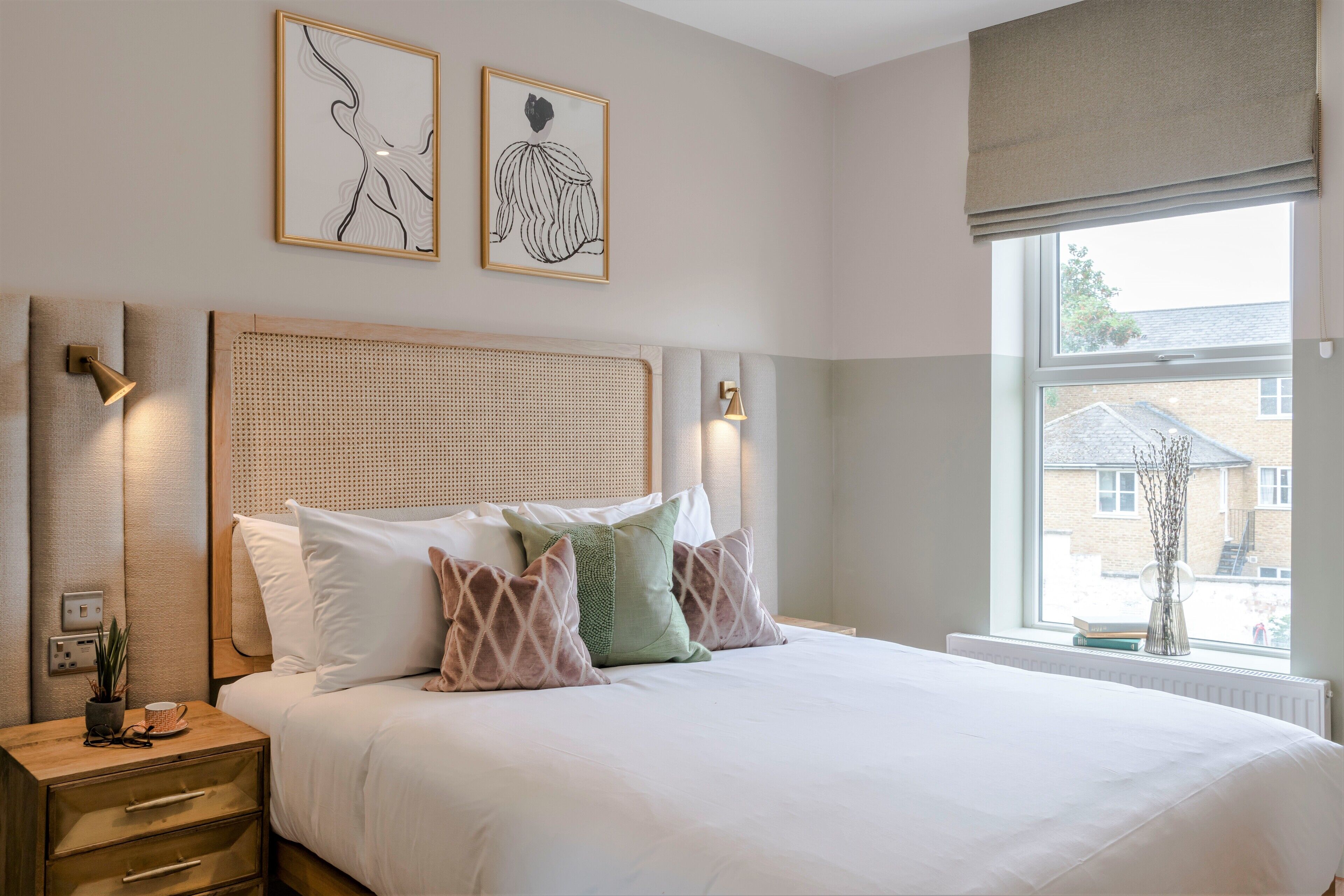 Een netjes ingerichte slaapkamer met een groot bed, bedlampjes en kunst aan de muur.