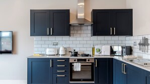 Una cocina moderna con armarios azul oscuro, horno empotrado y salpicadero de azulejos.