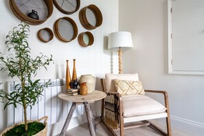 Cozy retreat with a rustic chair, table, and potted plant, surrounded by woven baskets and a warm radiator.