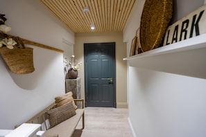 Enter room 3A through this inviting hallway, featuring a bench and a decorative vase with fresh flowers.