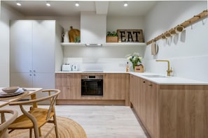 Kitchen features a stove, oven, sink, and dining area with a table and chairs.