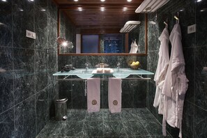 Une salle de bain moderne avec un lavabo en verre, des murs en marbre et un plafond en bois.