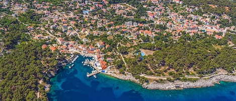 Vue aérienne d’une ville côtière avec des habitations densément regroupées, une marina et des eaux d’un bleu limpide.