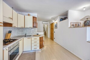 Une cuisine dotée d’un îlot central, de meubles en bois, d’un four encastré et d’une cuisinière à gaz.