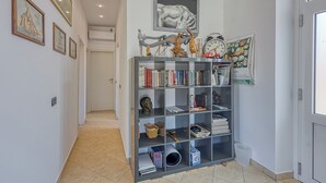 Un couloir avec une bibliothèque, des tableaux encadrés et une porte.