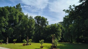 Ein Park mit Kiesweg, Kübelpflanzen und Statuen.