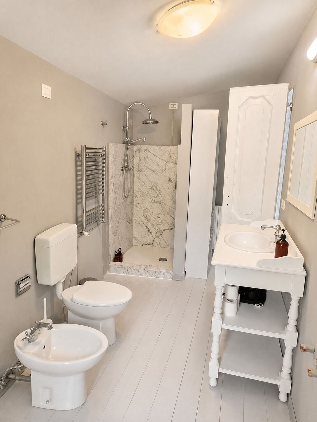 Une salle de bain comprenant des toilettes, un bidet, un lavabo et une douche.