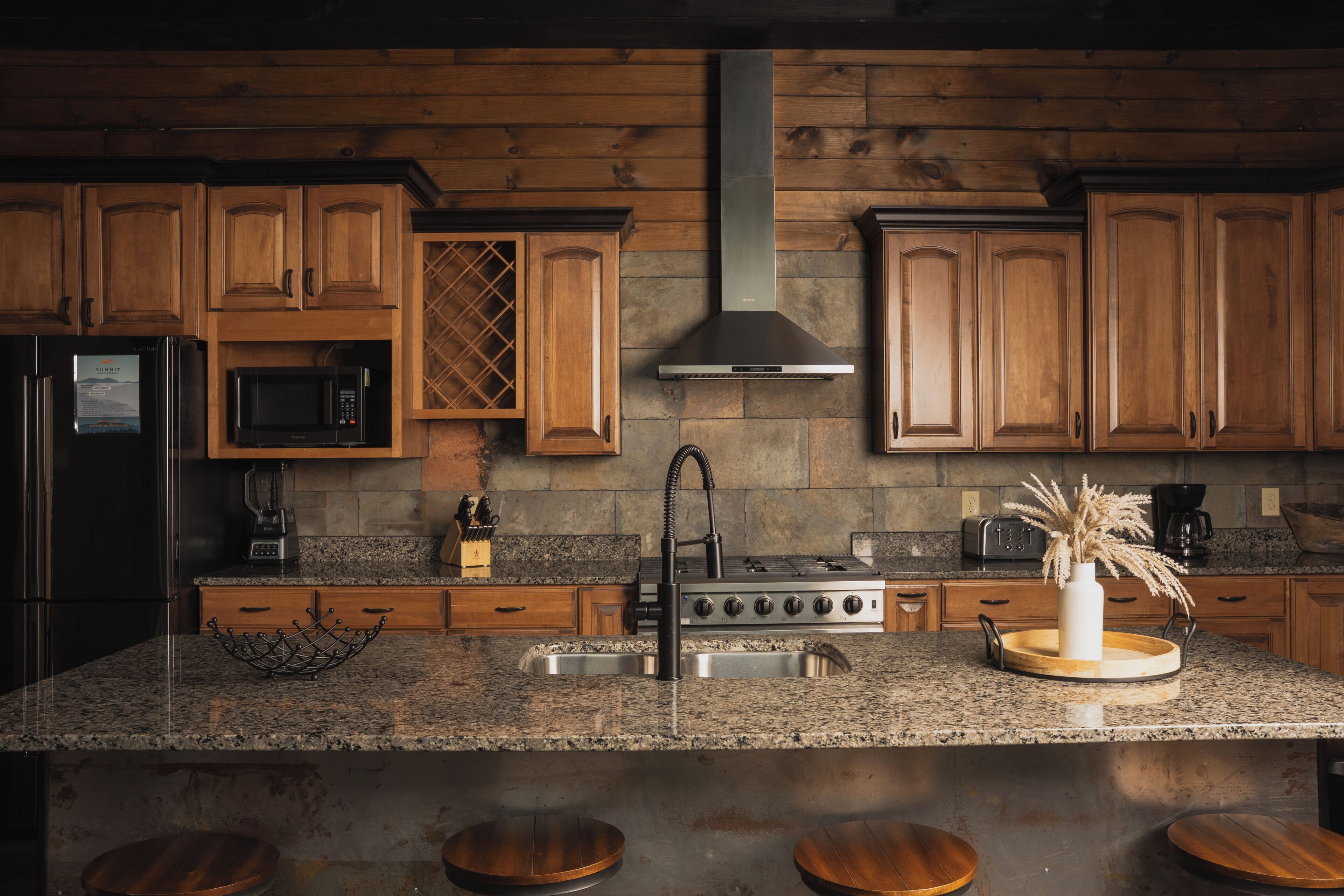 A kitchen with wooden cabinets, a stainless steel sink, a stove, a microwave, and a coffee maker.