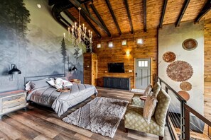 Un dormitorio con cama, candelabro, televisor y techo de madera.
