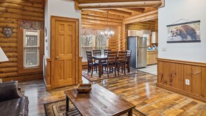 A log cabin interior with a dining area, kitchen, and living space.