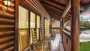 A wooden log cabin with a covered porch and several wooden benches.
