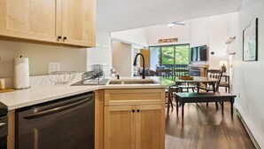 Eine moderne Küche mit Holzschränken, einem Geschirrspüler und einem Essbereich mit Tisch und Stühlen.