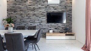 Ett modernt matområde med en vägg av sten, en platt-TV och en minimalistisk träkonsol.