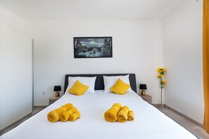 A hotel room with a large bed, two bedside tables with lamps, a painting on the wall, and a vase with flowers.