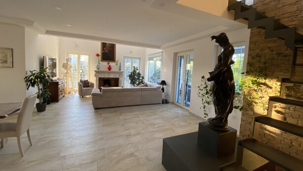 Un salon spacieux avec un grand canapé, une cheminée et une statue.