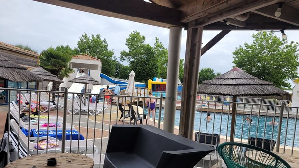 Un espace extérieur abrité comprenant des chaises longues, une piscine et un espace de jeux.