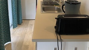 Une cuisine compacte équipée d’un four à micro-ondes, d’une cuisinière, d’un évier et d’un grille-pain posé sur le plan de travail.