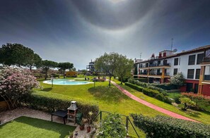 Un espacio exterior bien cuidado con piscina, parrilla y un camino pavimentado.