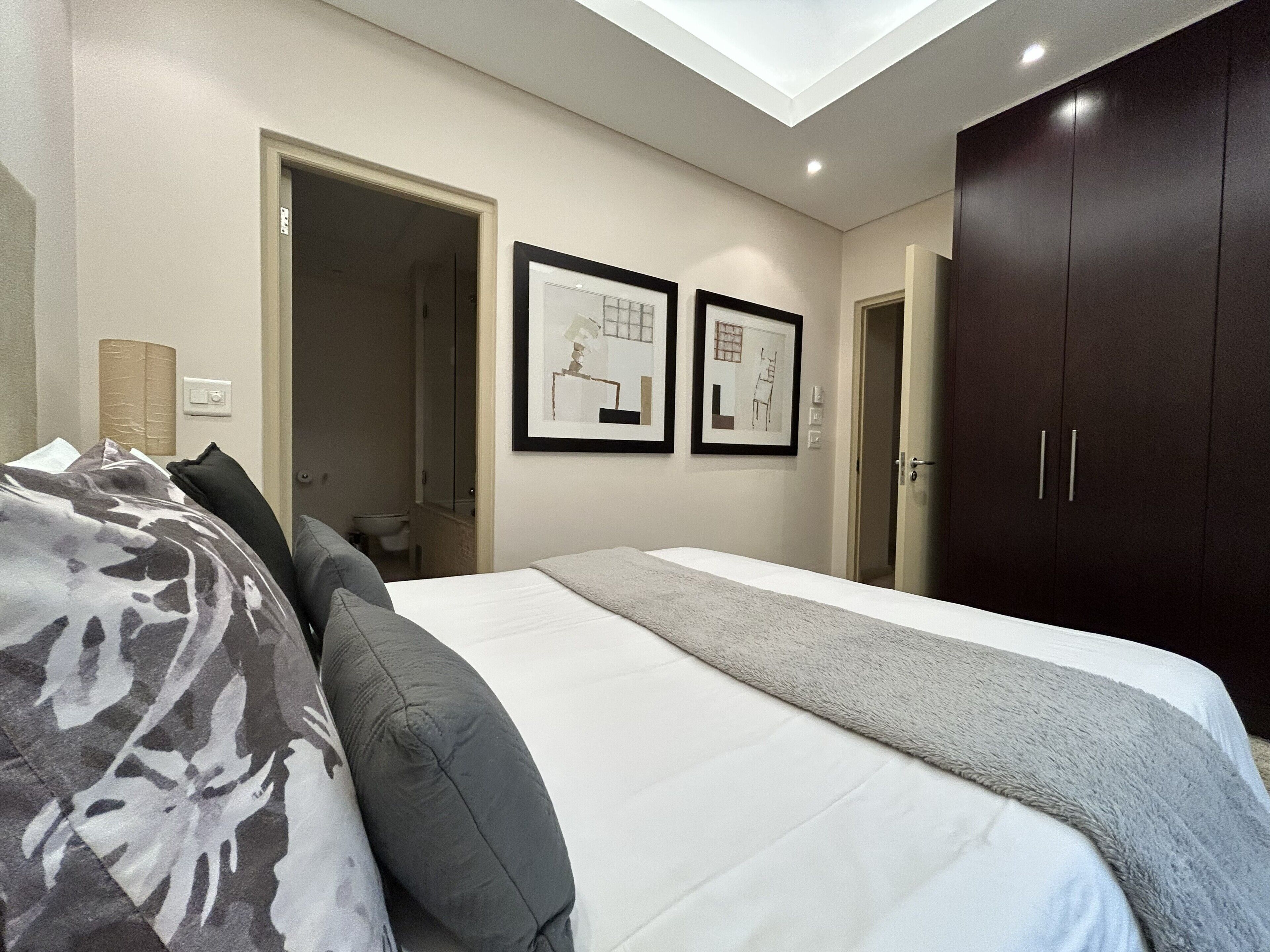 Une chambre à coucher avec un lit, une armoire et deux tableaux encadrés accrochés au mur.