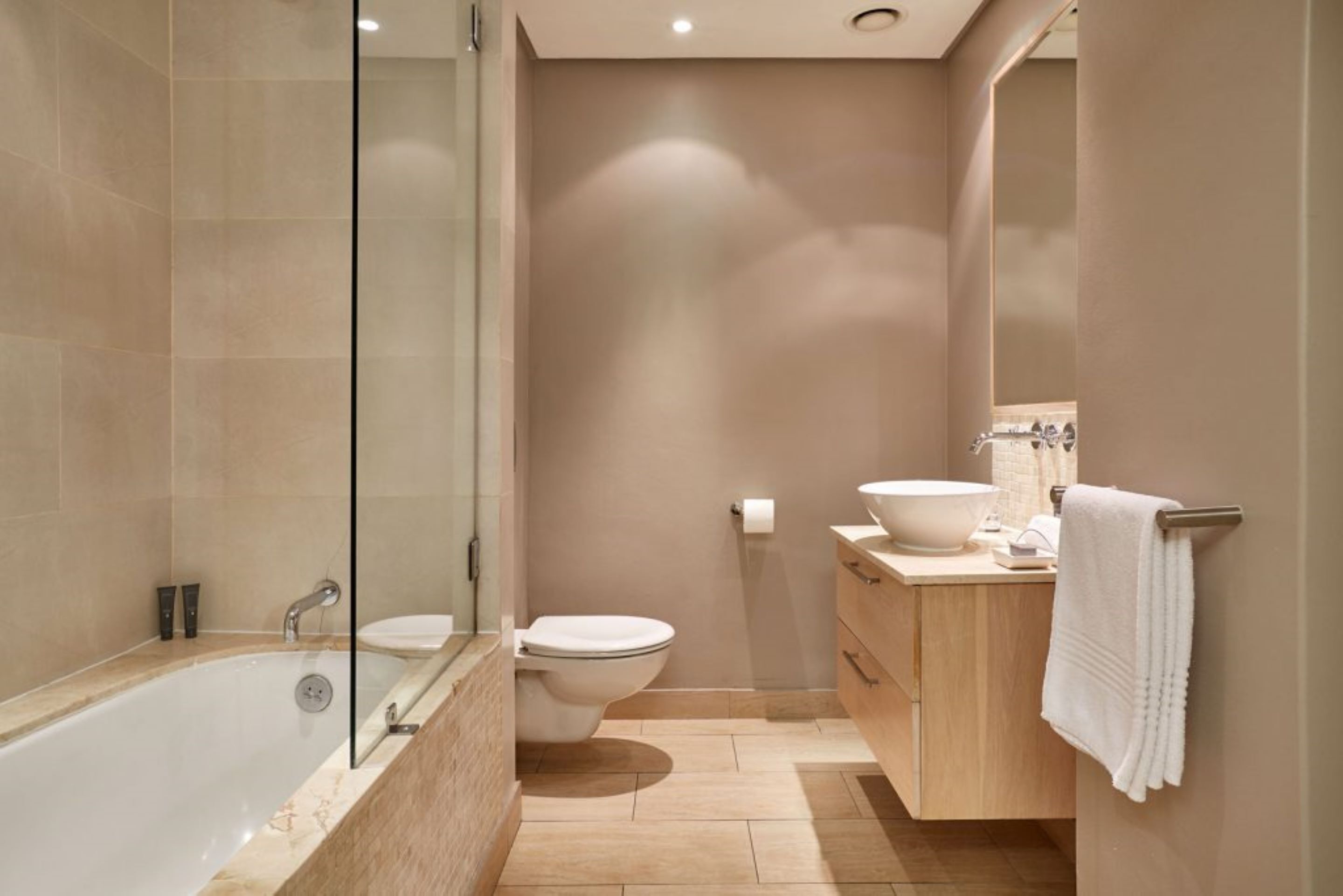 A modern bathroom with a bathtub, toilet, and vanity.