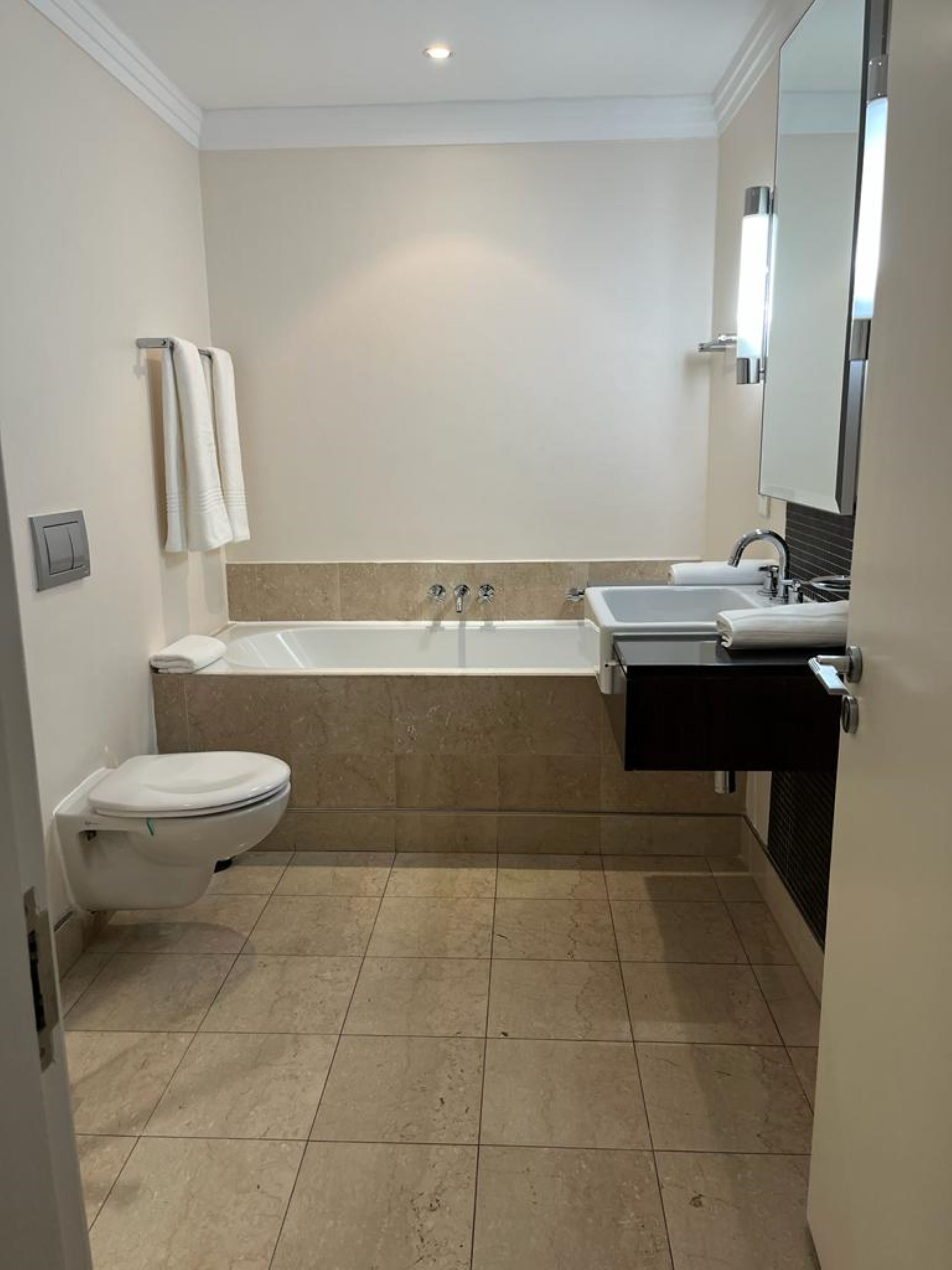 A modern bathroom with a bathtub, two sinks, and a toilet.
