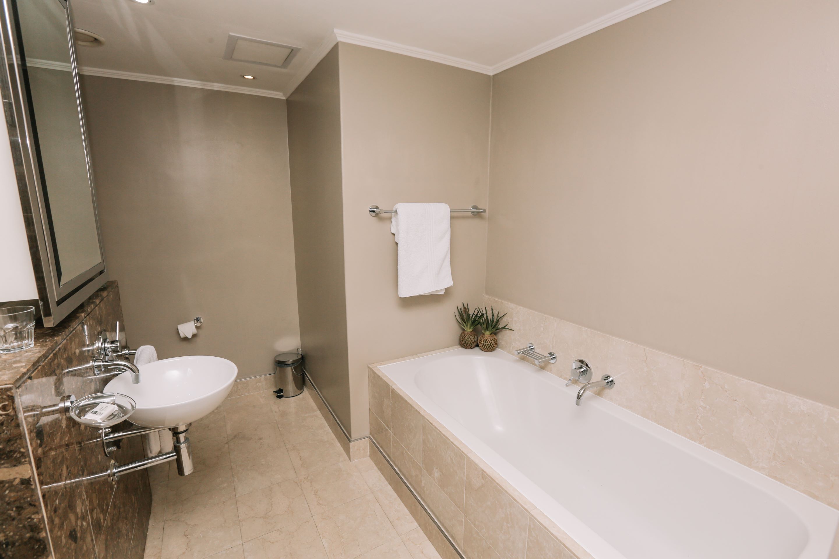 A modern bathroom with a sink, mirror, and bathtub.