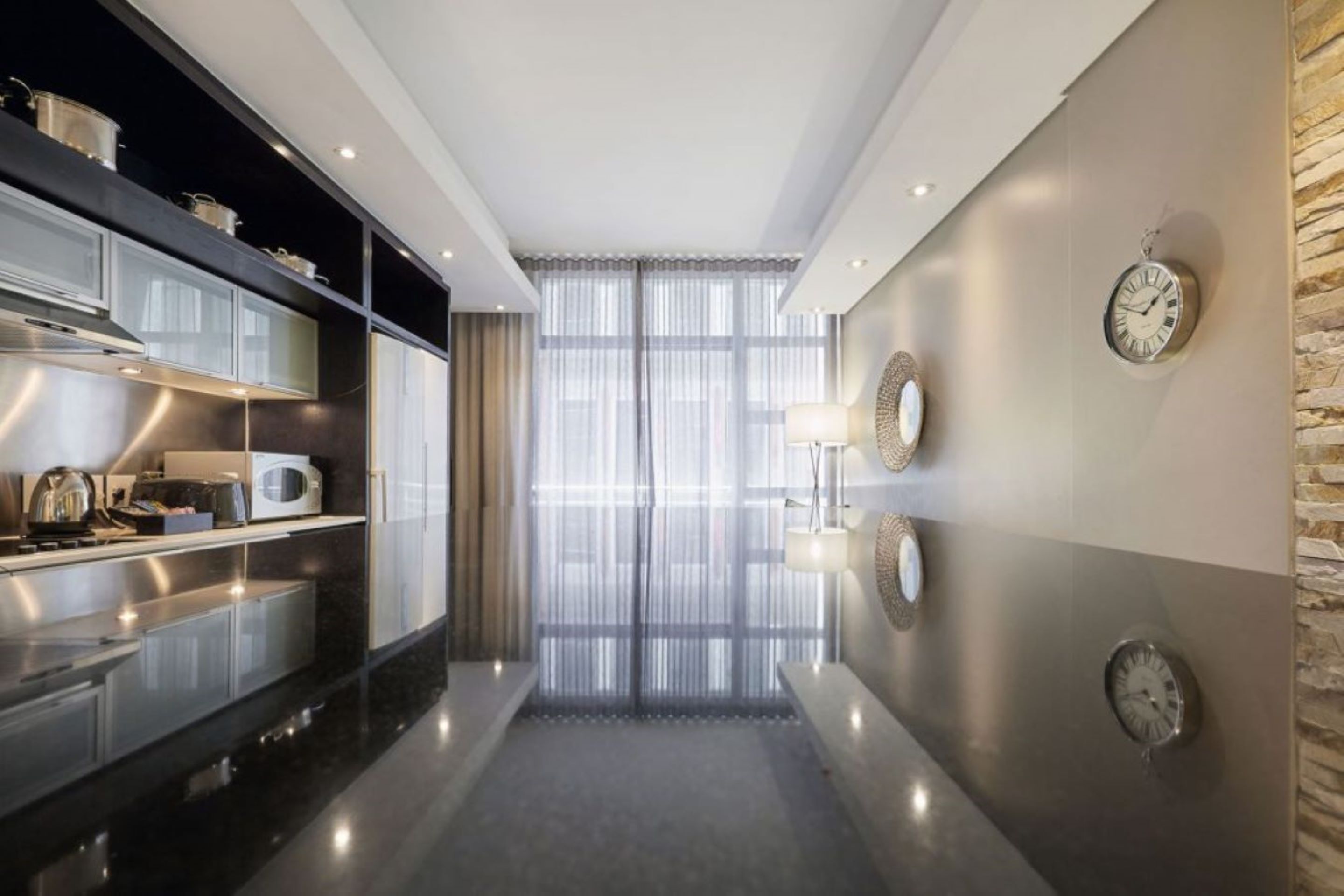 A modern kitchen with stainless steel appliances, a reflective backsplash, and a view into the dining area.