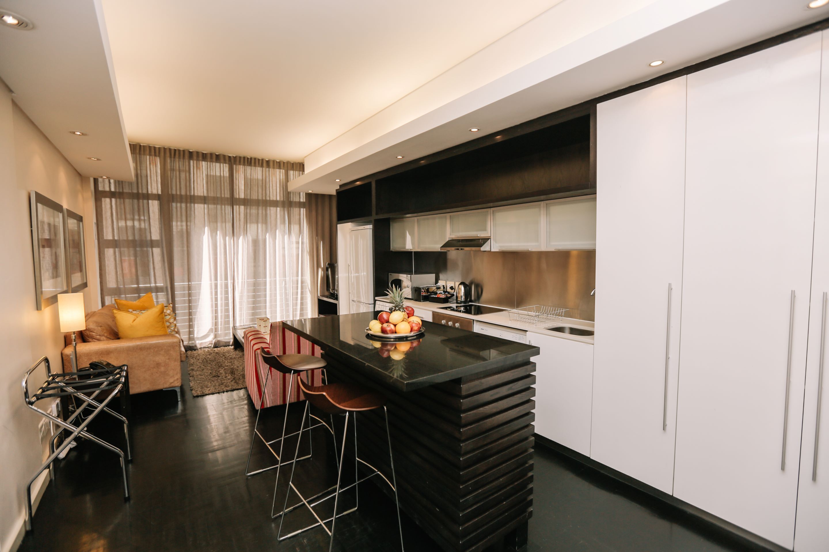 Une cuisine moderne dotée d’un îlot central, de tabourets de bar et d’un coin repas comprenant un canapé et une table basse.