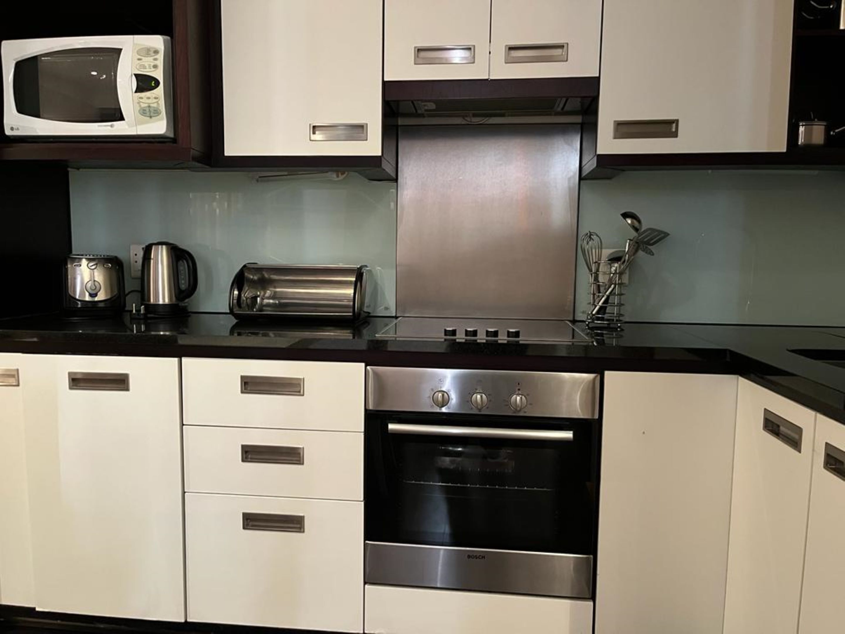 Una cocina equipada con microondas, tostadora, hervidor y horno Bosch.