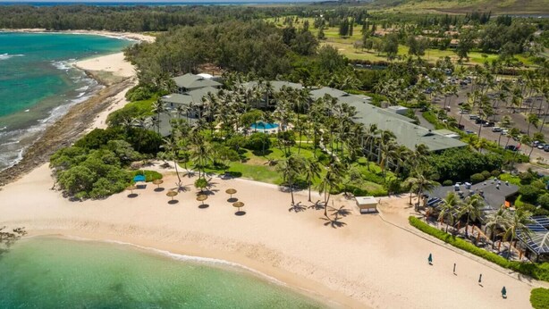 An aerial view of a resort with a beachfront, palm trees, and a golf course in the background. - Presidential Suites • Turtle Bay 4BR Oceanfront Villa (Kahuku)