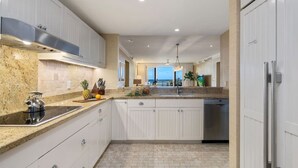 A modern kitchen with white cabinetry, granite countertops, and a stainless steel range hood. - Presidential Suites • Turtle Bay 4BR Oceanfront Villa (Kahuku)