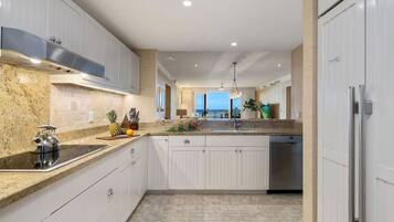 A modern kitchen with white cabinetry, granite countertops, and a stainless steel range hood.
