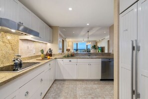 Una cocina moderna con armarios blancos, encimeras de granito y una campana extractora de acero inoxidable.