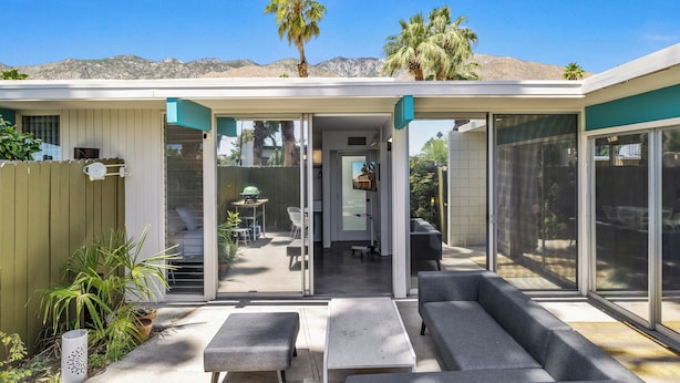 A covered patio with a seating area, a glass door leading to a patio, and a view of a mountain range. - 1957 Modern Hideaway - A Ryson Property (Palm Springs)