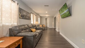 A modern living room with a grey leather sofa, a wooden coffee table, and a TV mounted on the wall. - Lemon Drop Lane condo on Table Rock Lake! (Branson)
