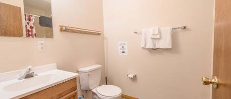 Un bagno piccolo con lavandino, wc e specchio bianchi. C'è un portasciugamani sulla parete e un pavimento in legno.