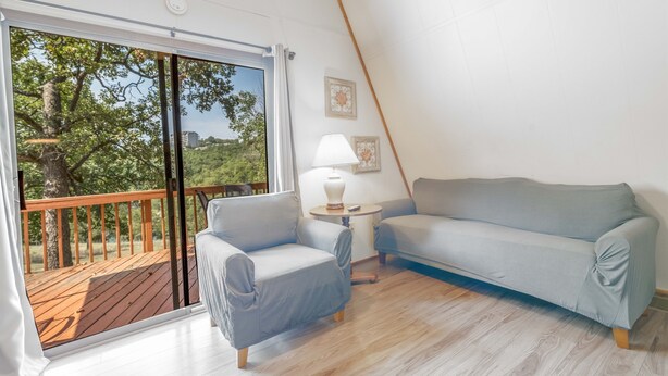 Ein Zimmer mit einer Holzterrasse, einem Sofa, einem Sessel und einer Lampe.