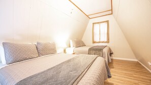 A bedroom with two beds, wooden flooring, and a sloped ceiling. - A-Frame Cabin on Table Rock Lake, by SDC! (Branson)